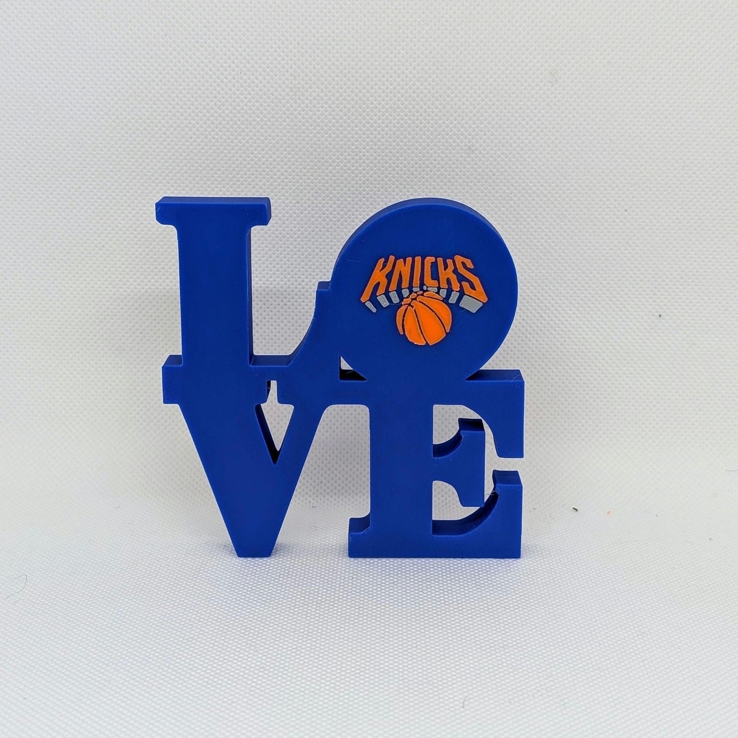 Blue decorative letter 'E' with Knicks logo on a white background