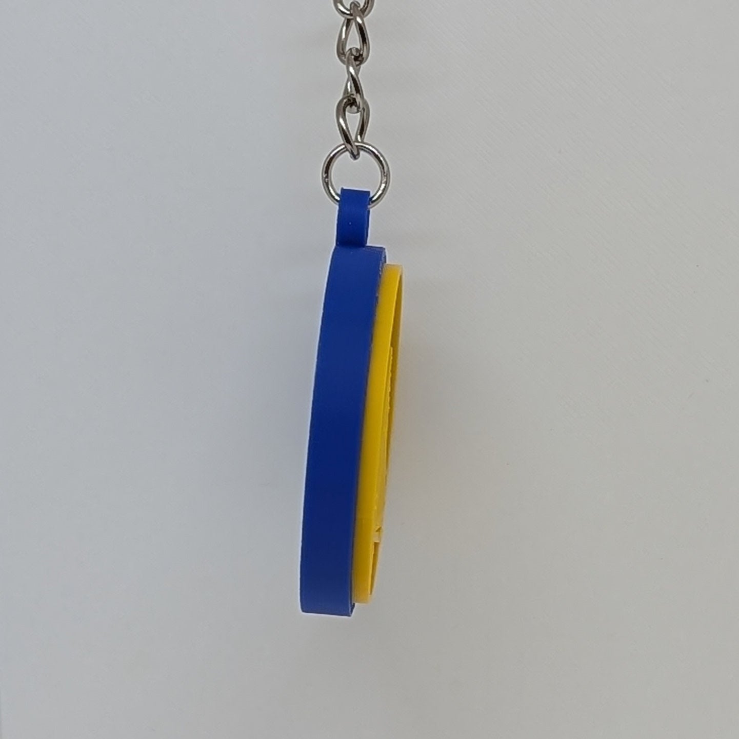 Blue and yellow keychain on a white stand against a white background