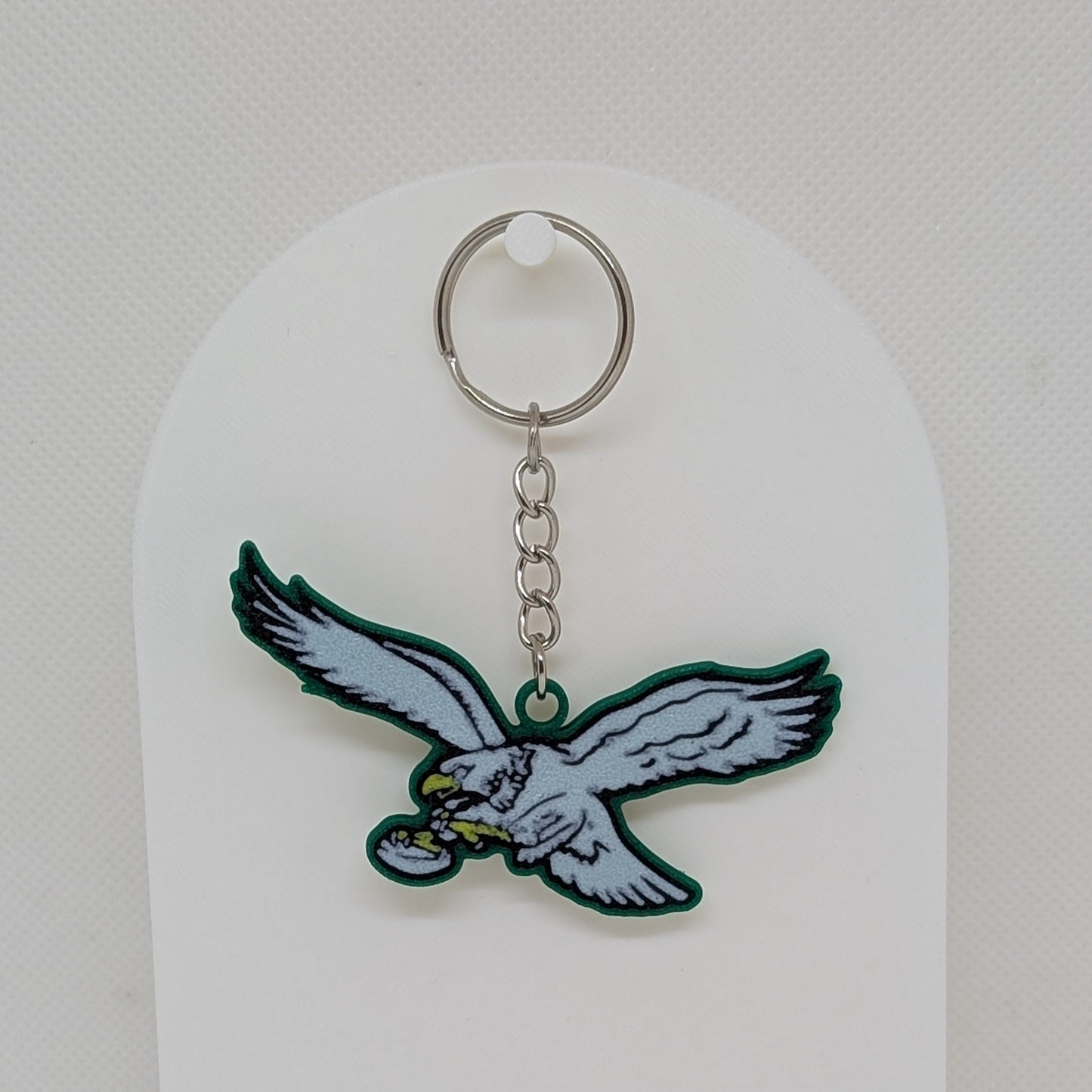 Keychain with an eagle design on a white stand against a white background