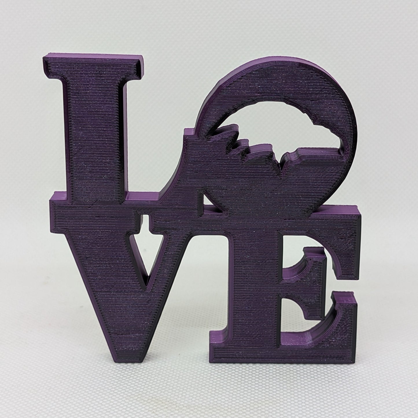 Purple 'LOVE' decorative item on a white background