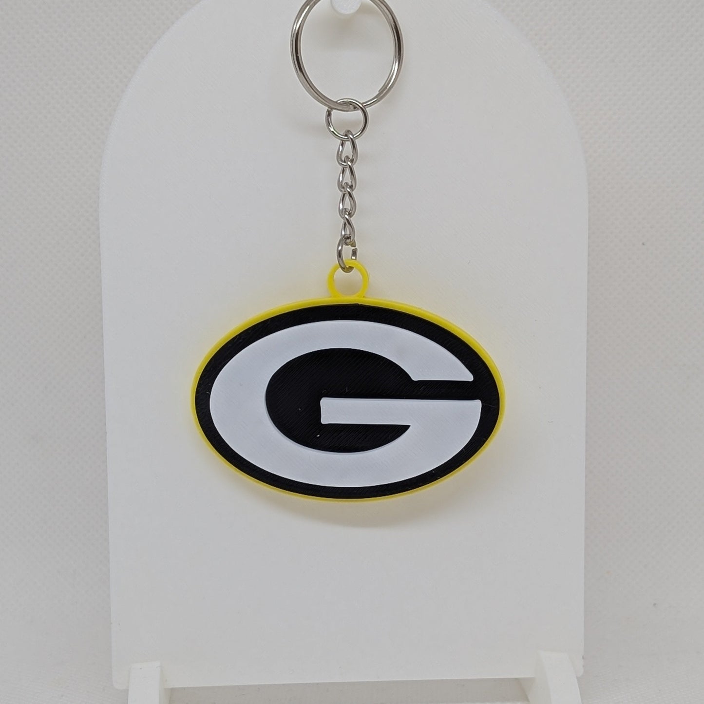 Packers Keychain with a logo on a white stand against a light gray background