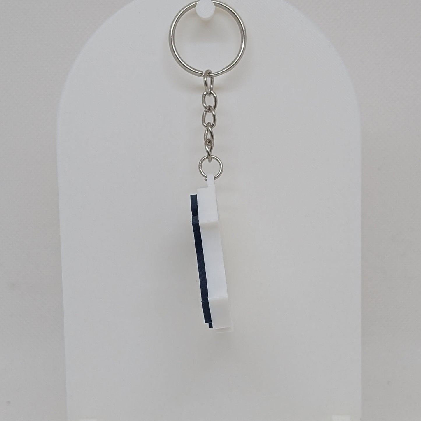 Keychain with a white and blue tag on a white stand against a white background