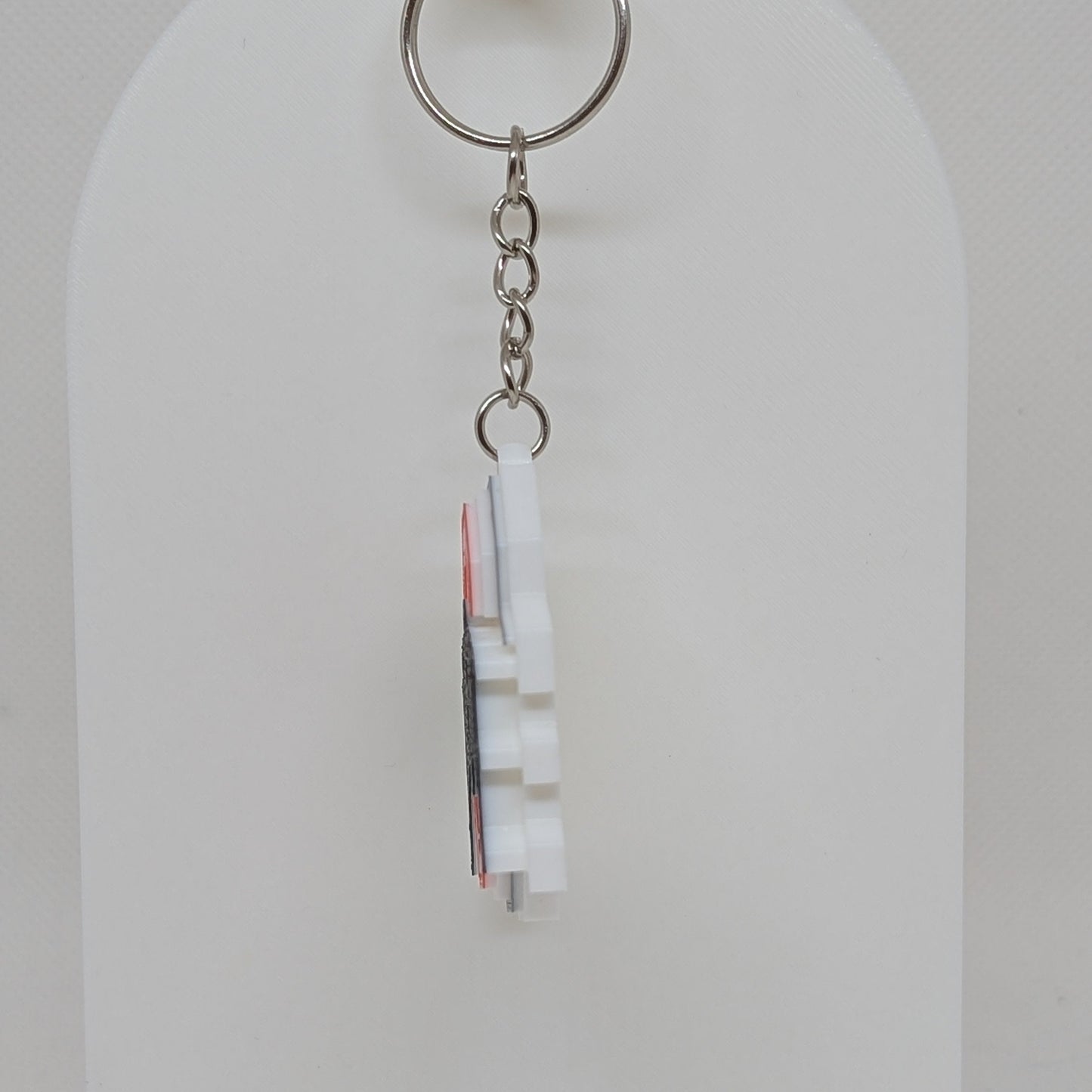 Keychain with a small flag design on a white stand against a light gray background