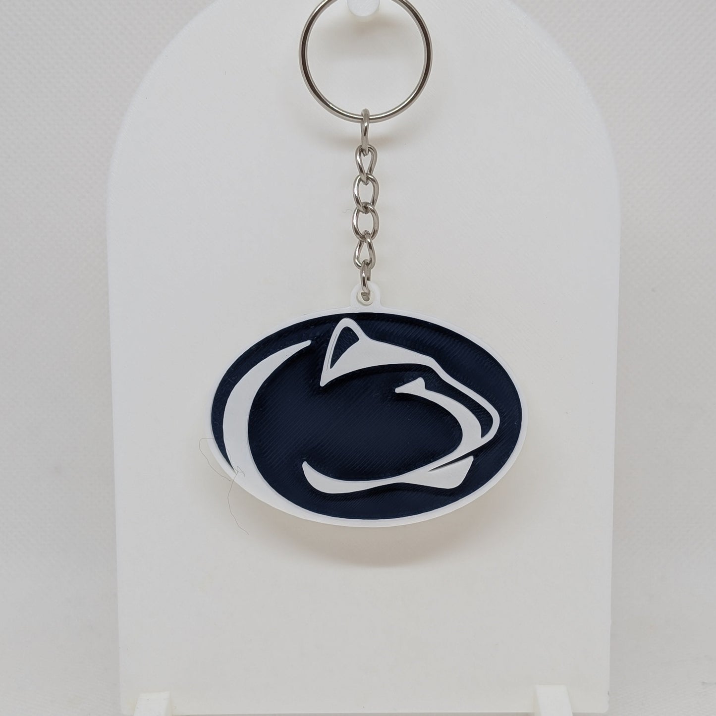 Penn State Keychain with a logo on a white stand against a white background