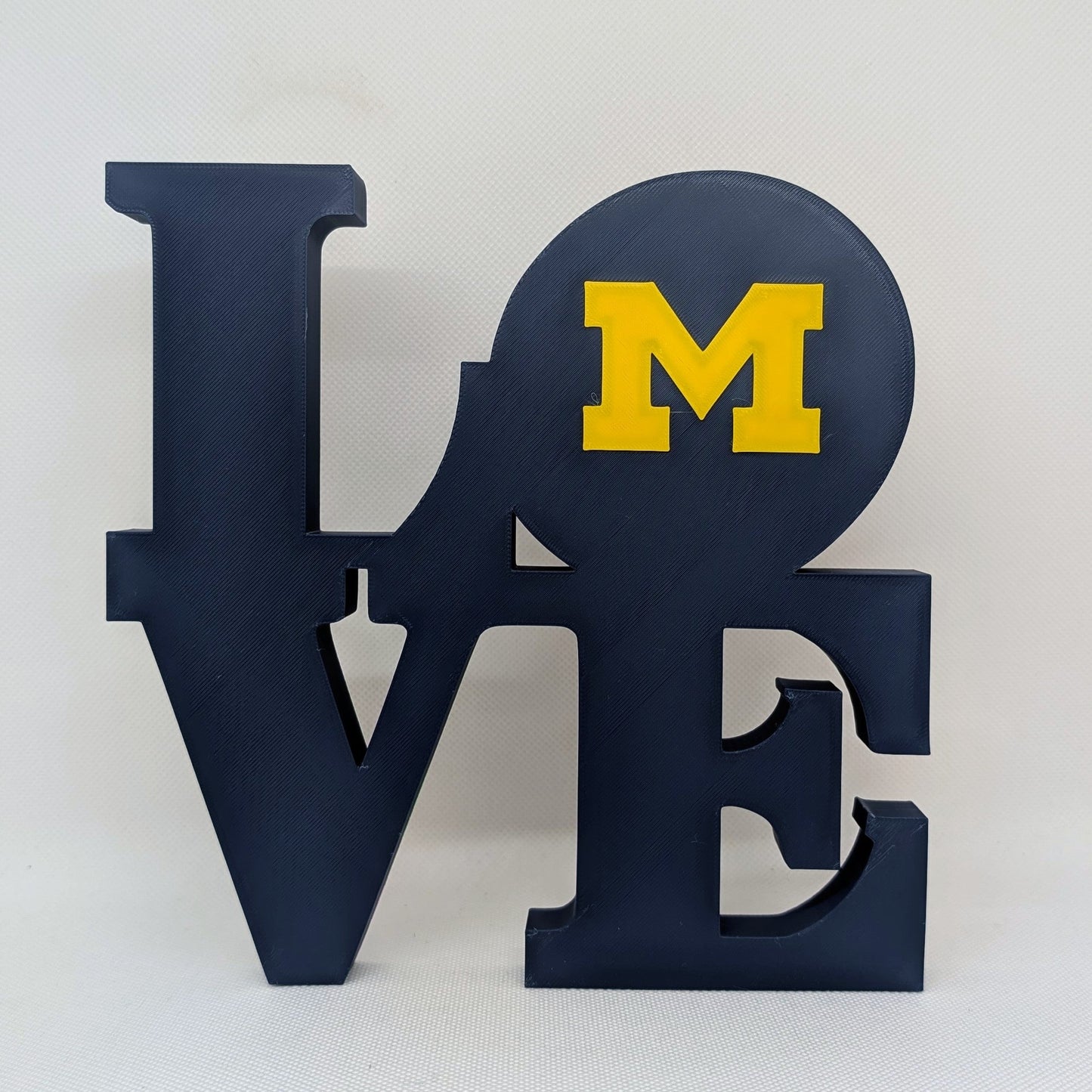 Navy 'LOVE' sign with a yellow 'M' on a white background