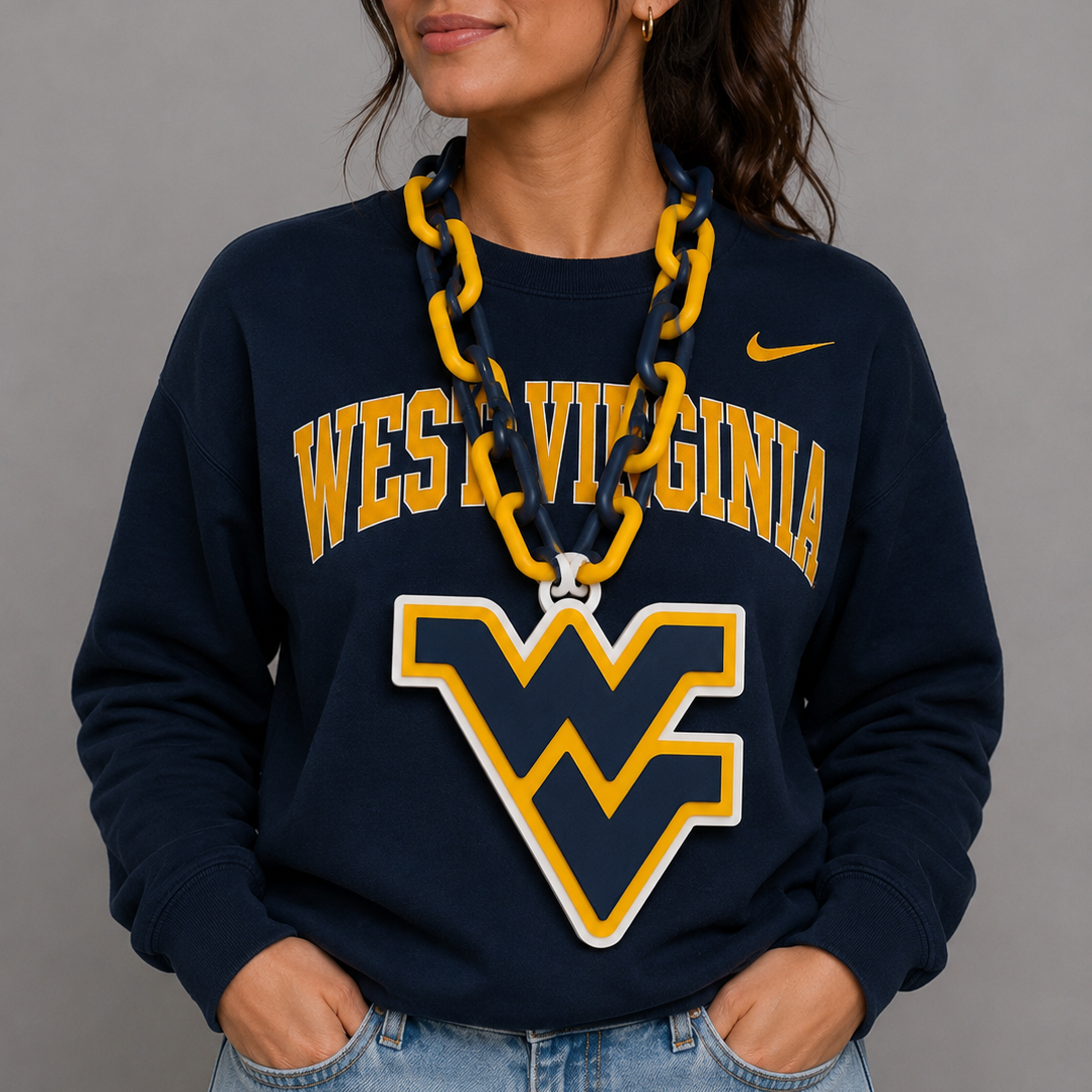 A woman wearing a navy blue West Virginia University sweatshirt with a large yellow and white 'WV' logo on the front, paired with light blue jeans and a chunky yellow-and-blue chain necklace, against a solid gray studio background.