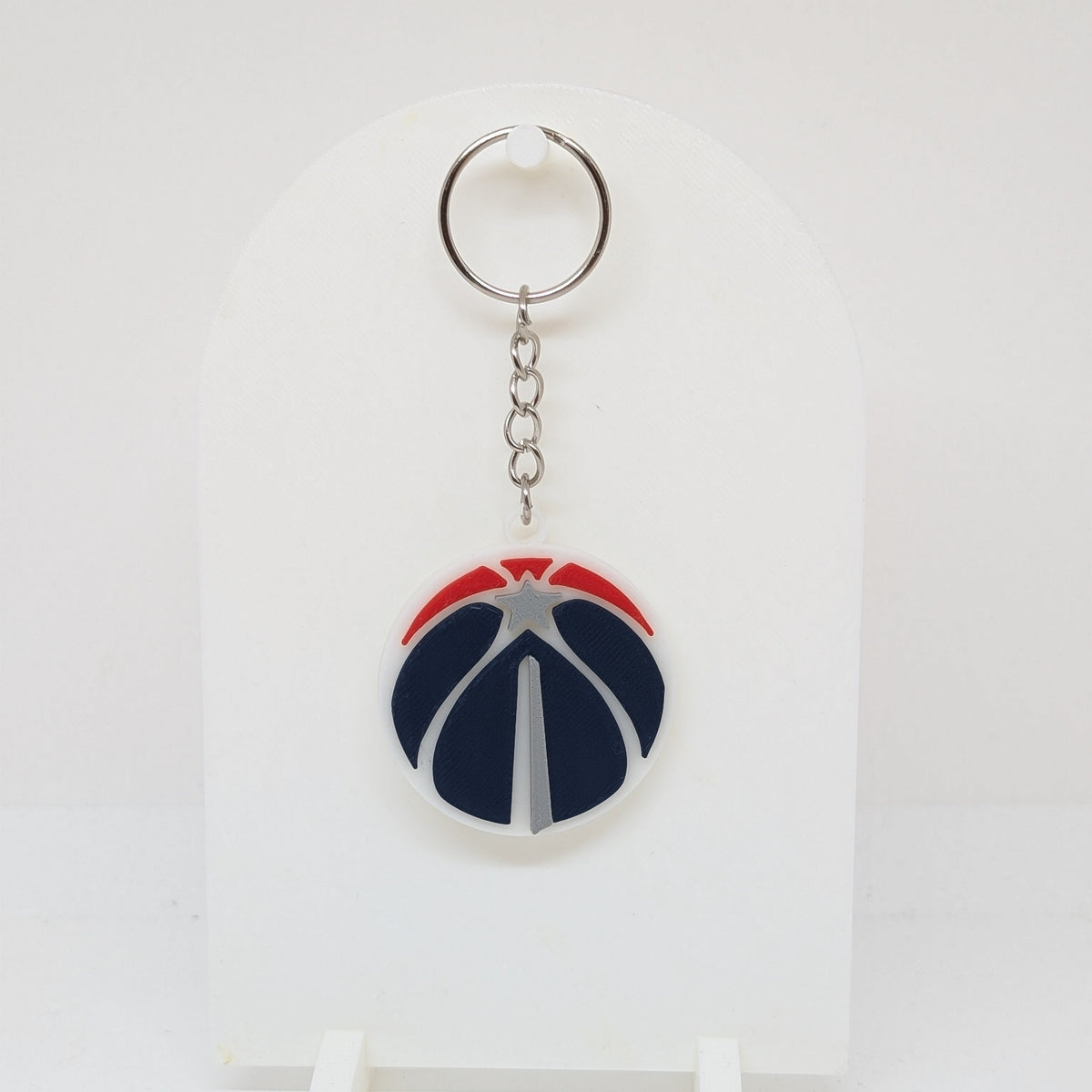 A Washington Capitals keychain featuring a glossy basketball-shaped charm with the team's logo, displayed on a white stand against a white background.