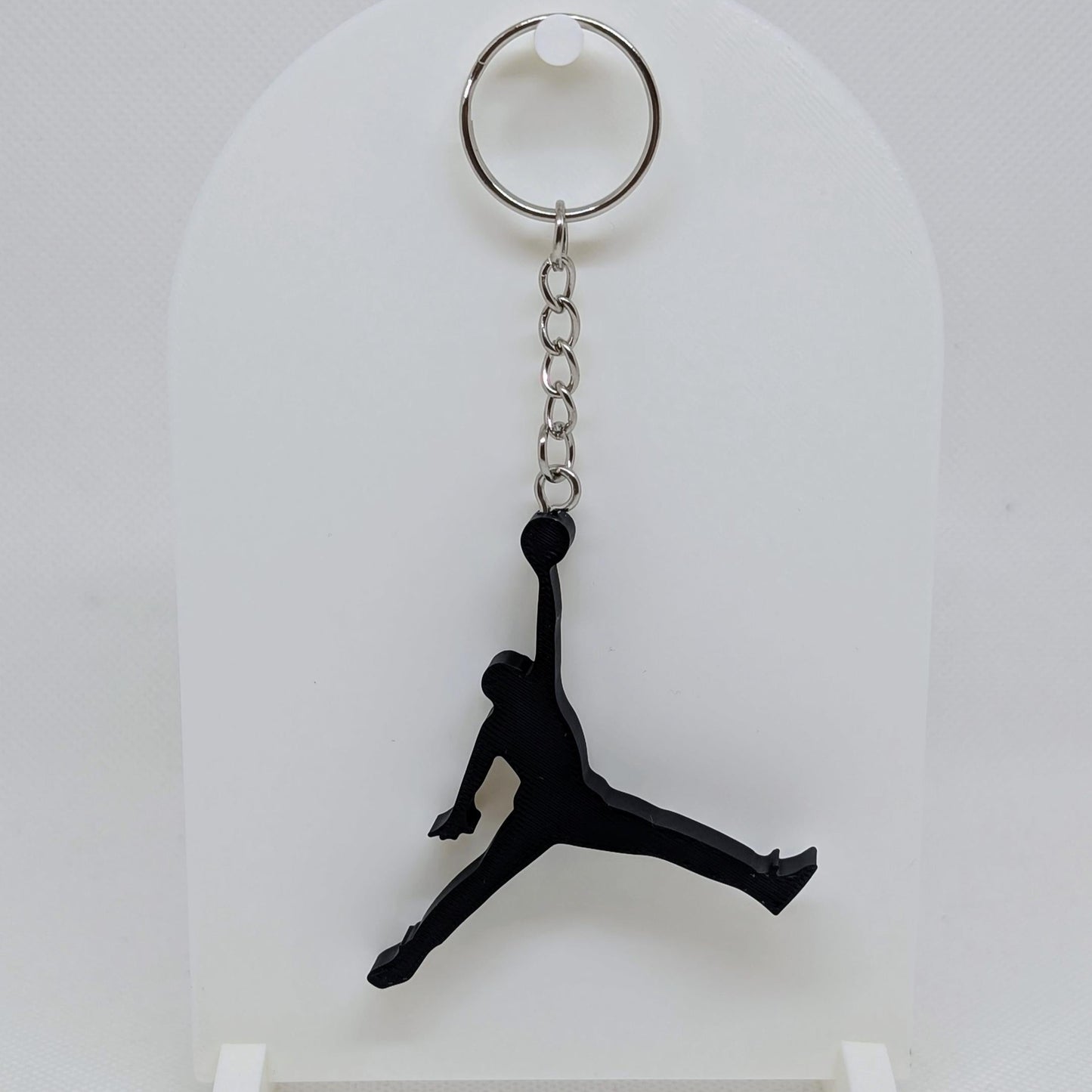 Black silhouette keychain on a white stand with a white background