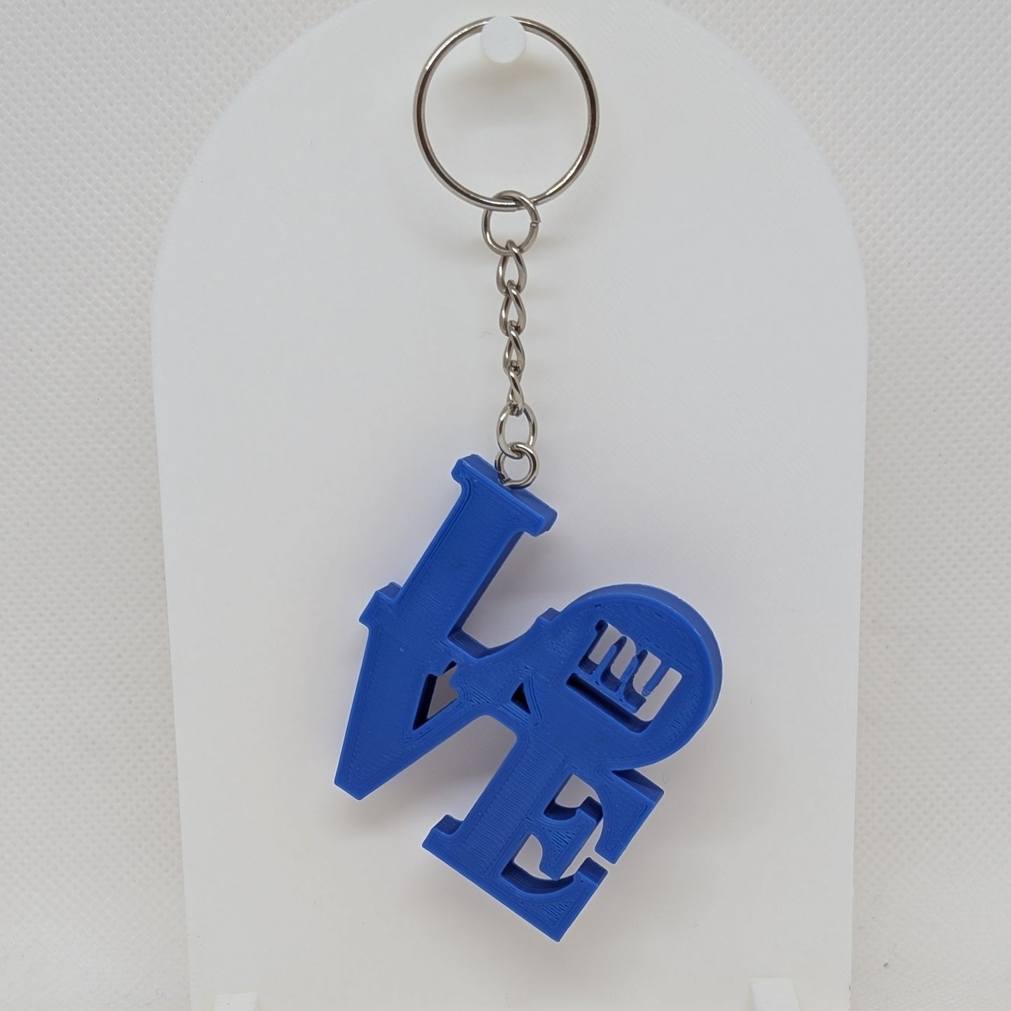Giants Blue 'LOVE' keychain on a white stand with a white background