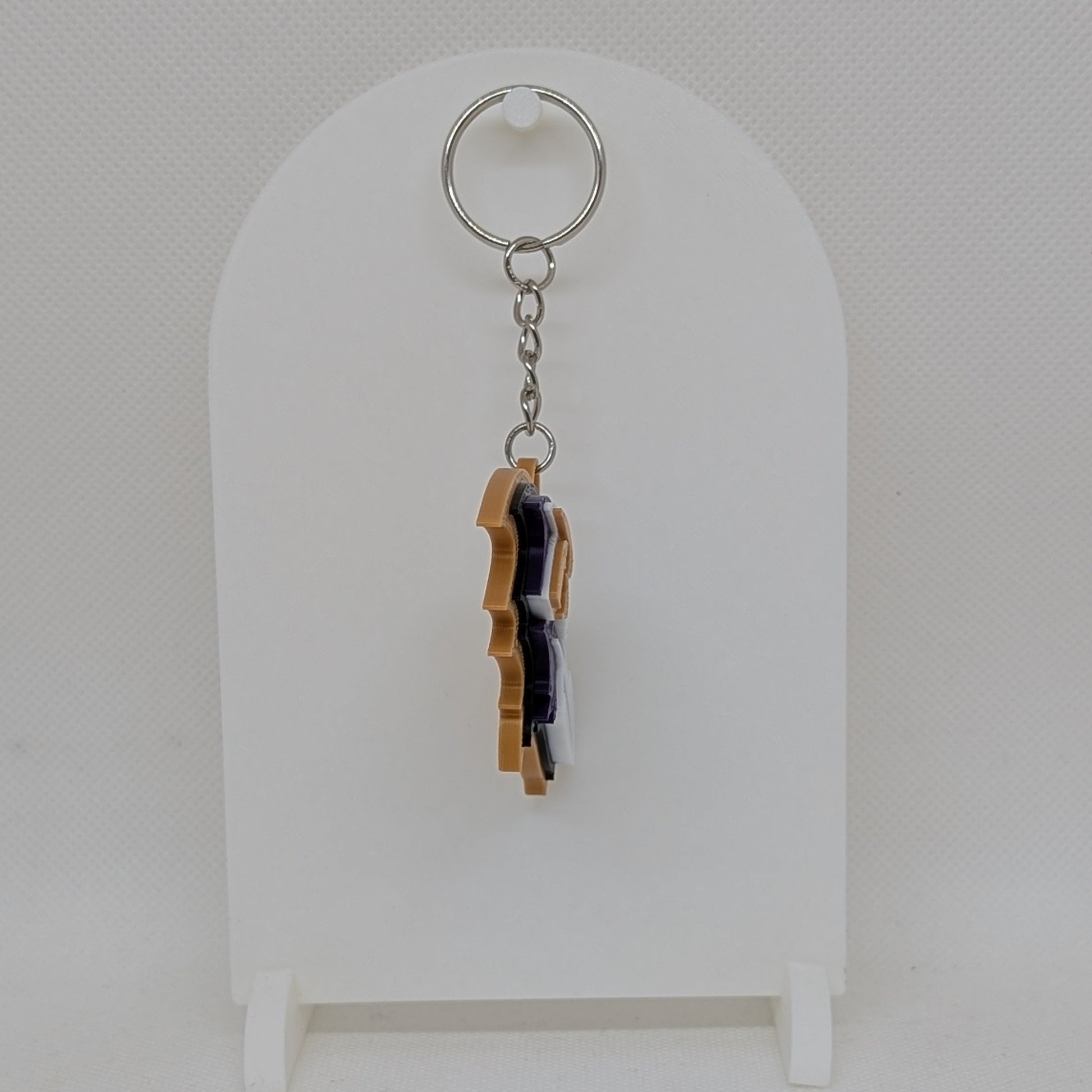 Keychain with a small figurine on a white stand against a light gray background