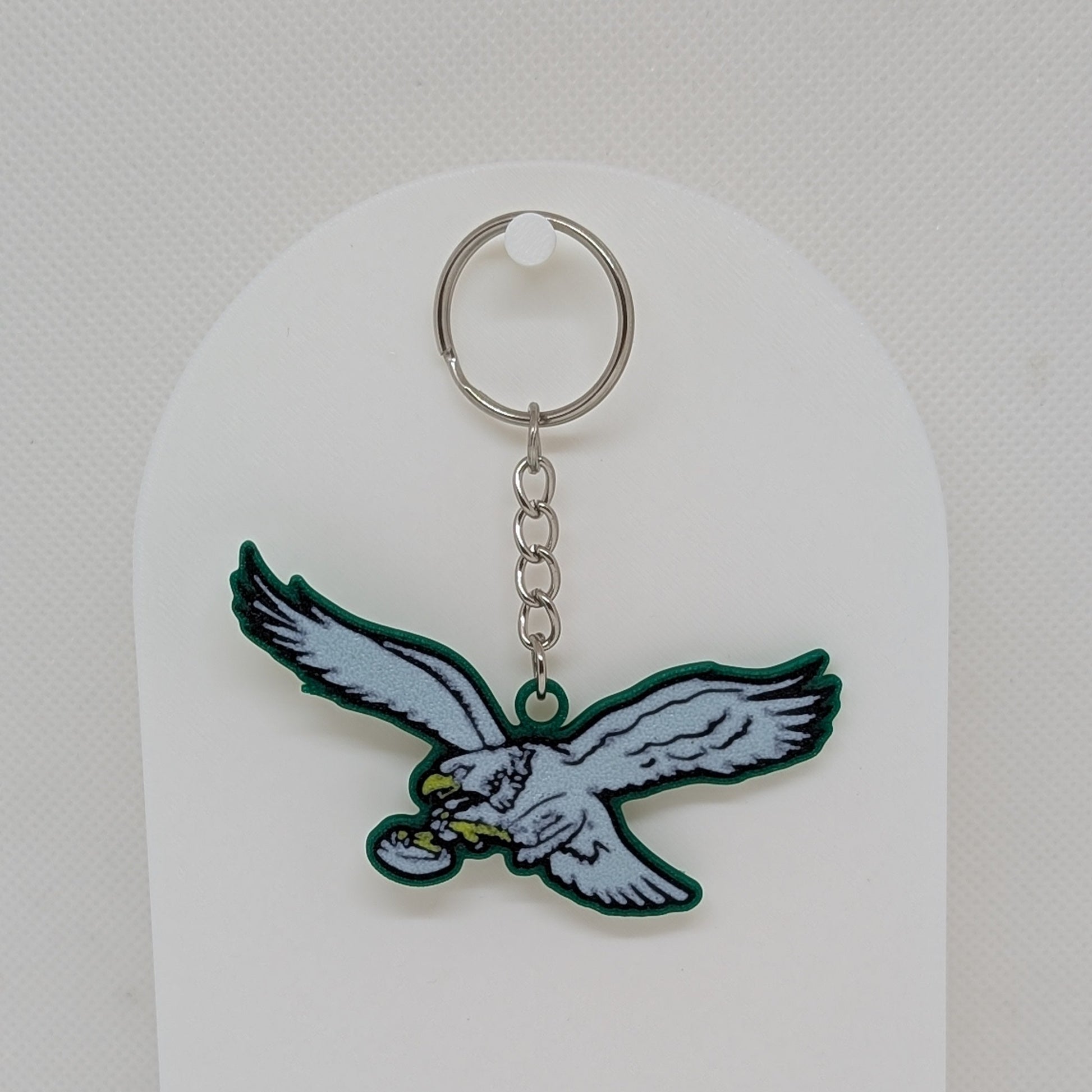 Keychain with an eagle design on a white stand against a white background