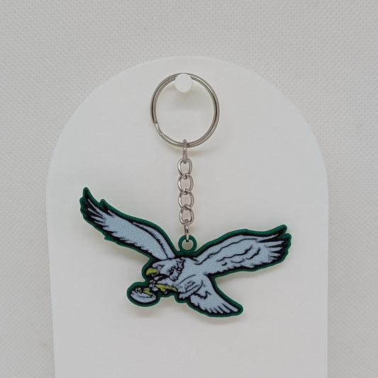 Keychain with an eagle design on a white stand against a white background