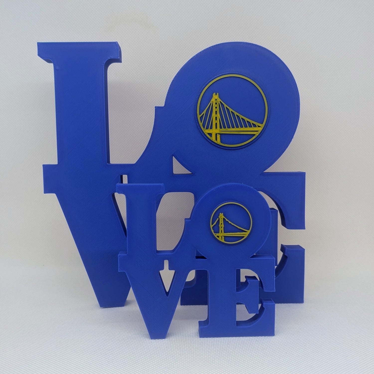 Blue decorative letters spelling 'LOVE' with a yellow logo on a white background