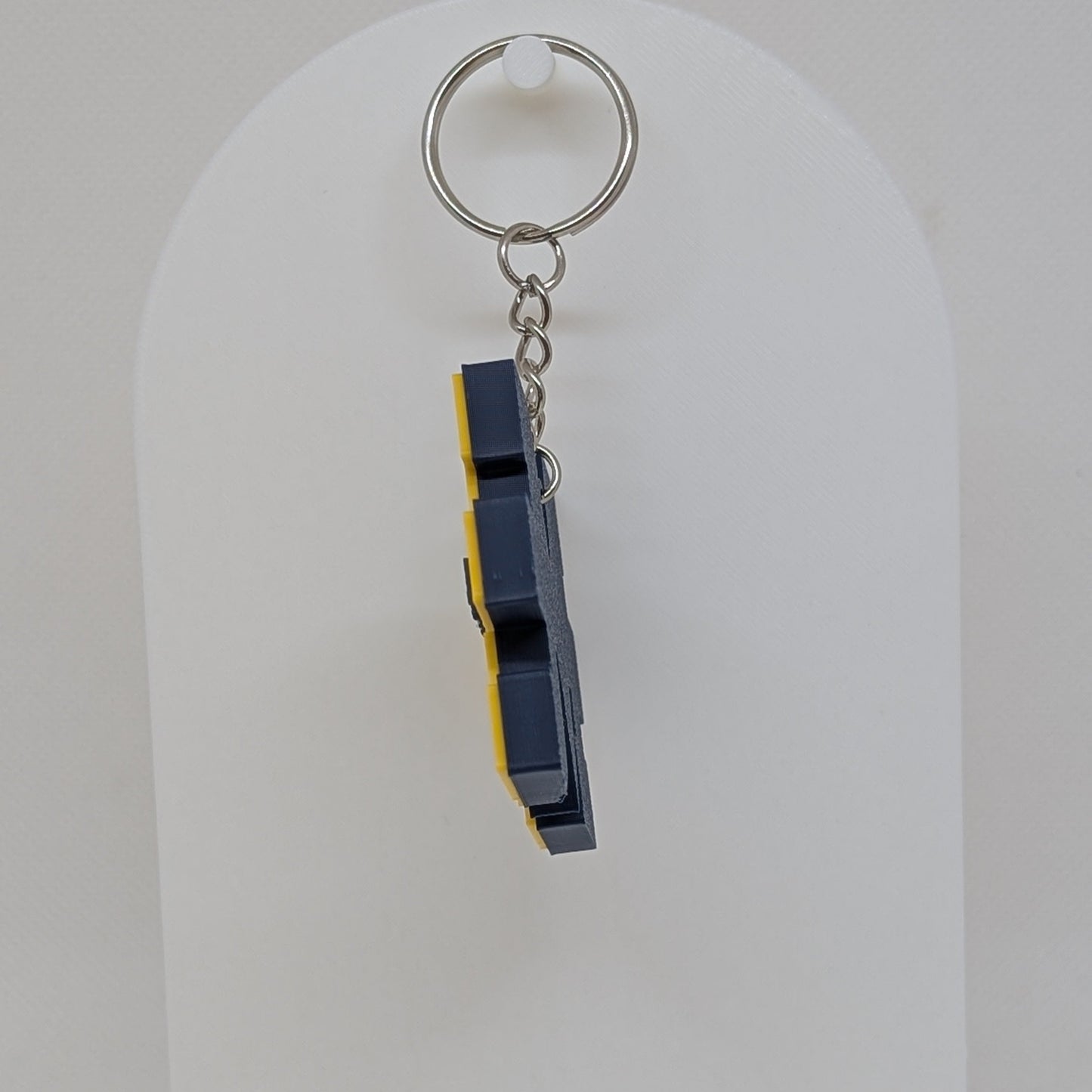 Keychain with a blue and yellow design on a white stand against a white background