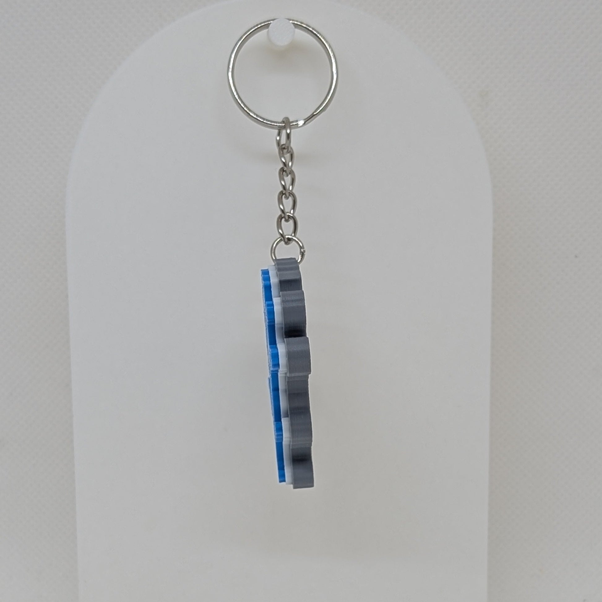 Keychain with striped design on a white stand against a light gray background