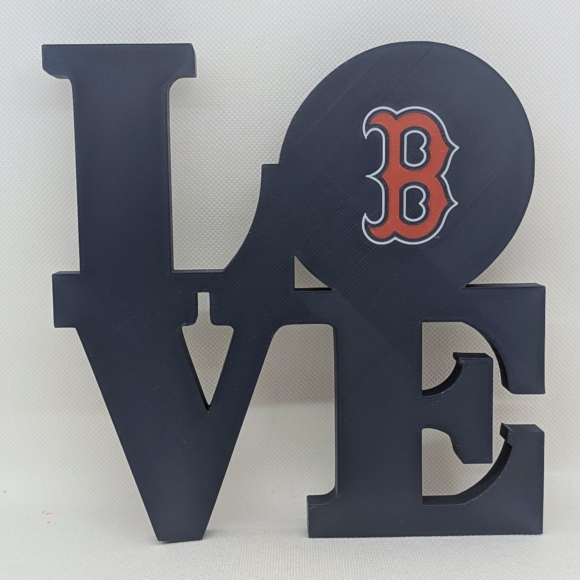 Decorative wall art with 'LOVE' letters and a red 'B' on a white background