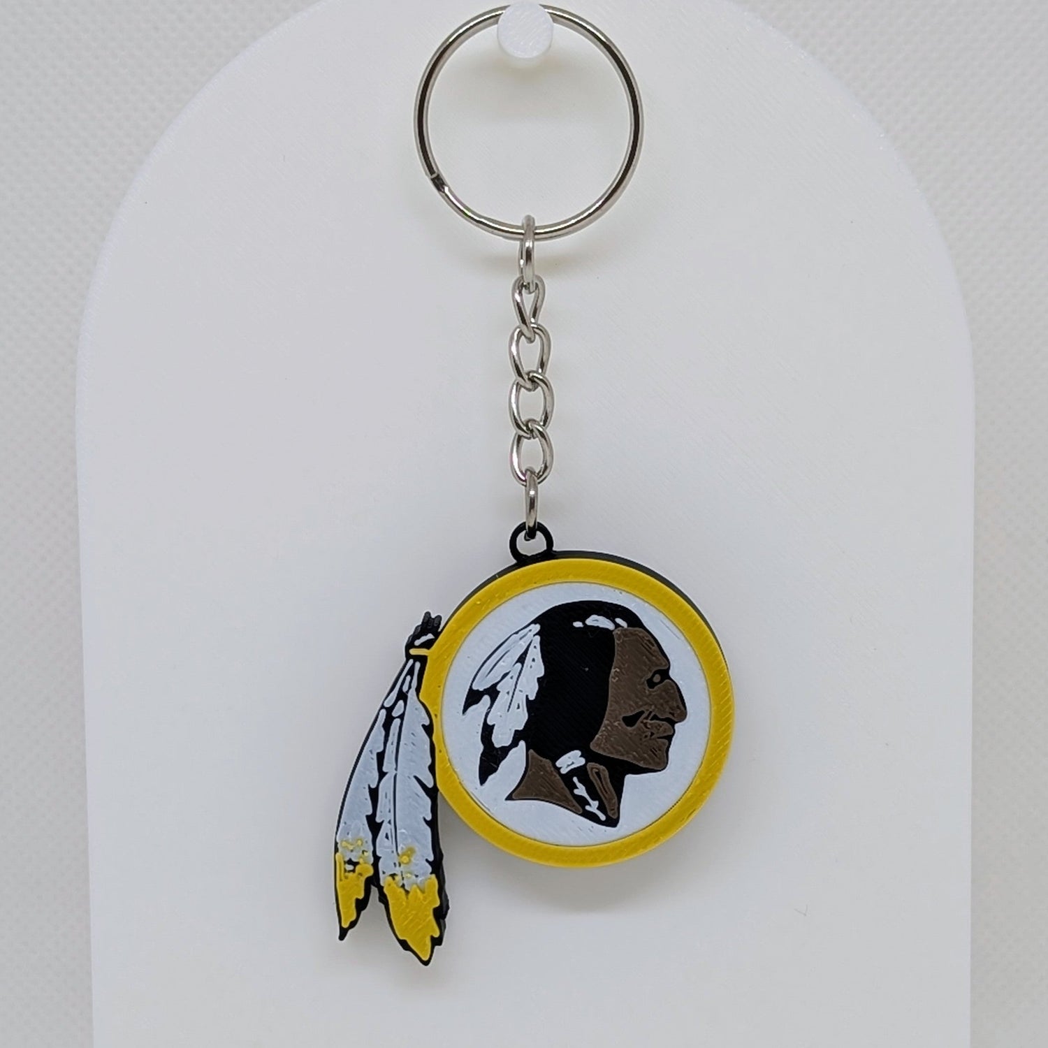 Redskins Keychain with a logo featuring a face and feathers on a white background
