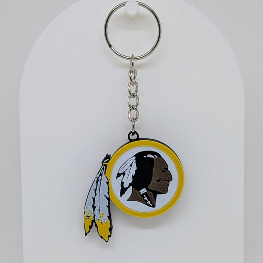 Redskins Keychain with a logo featuring a face and feathers on a white background