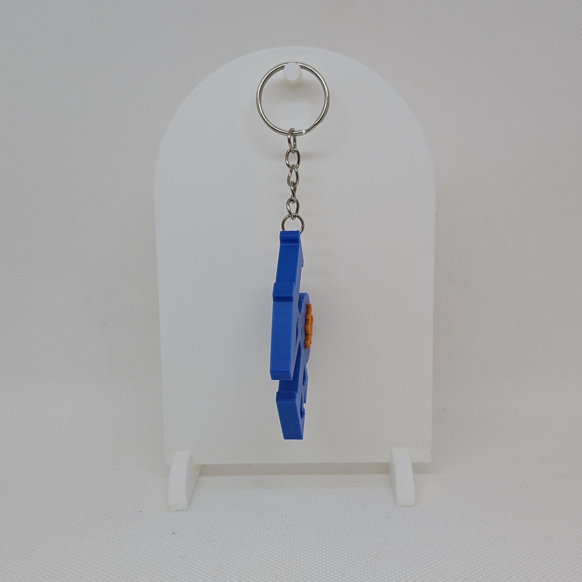 Blue keychain with a small object on a white stand against a white background