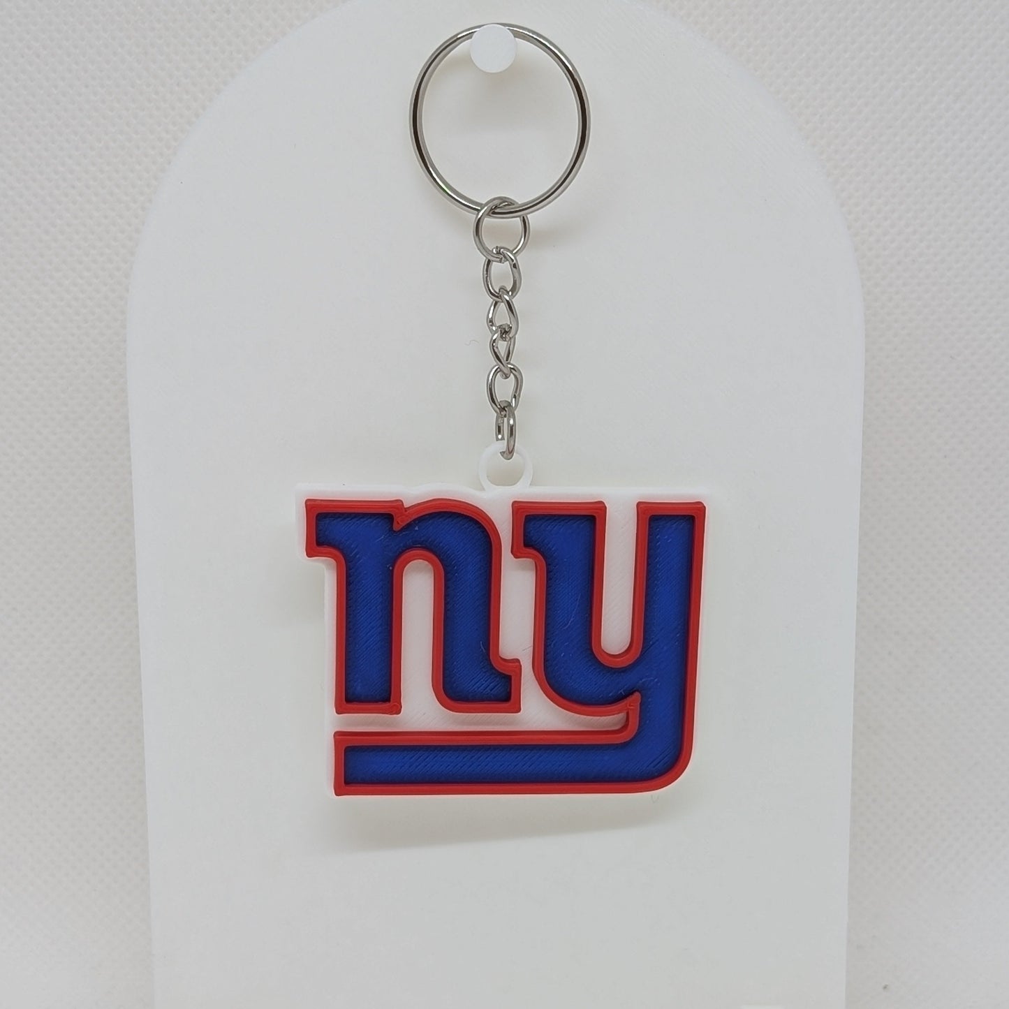 Keychain with 'ny' Giants logo on a white stand against a white background