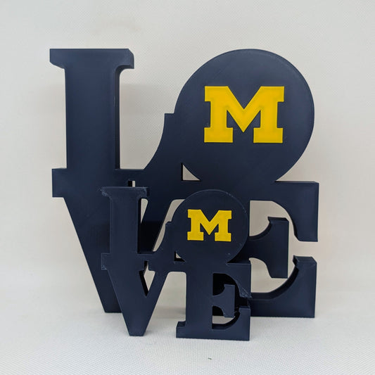 Decorative sign with 'LOVE' in blue and 'M' in yellow on a white background