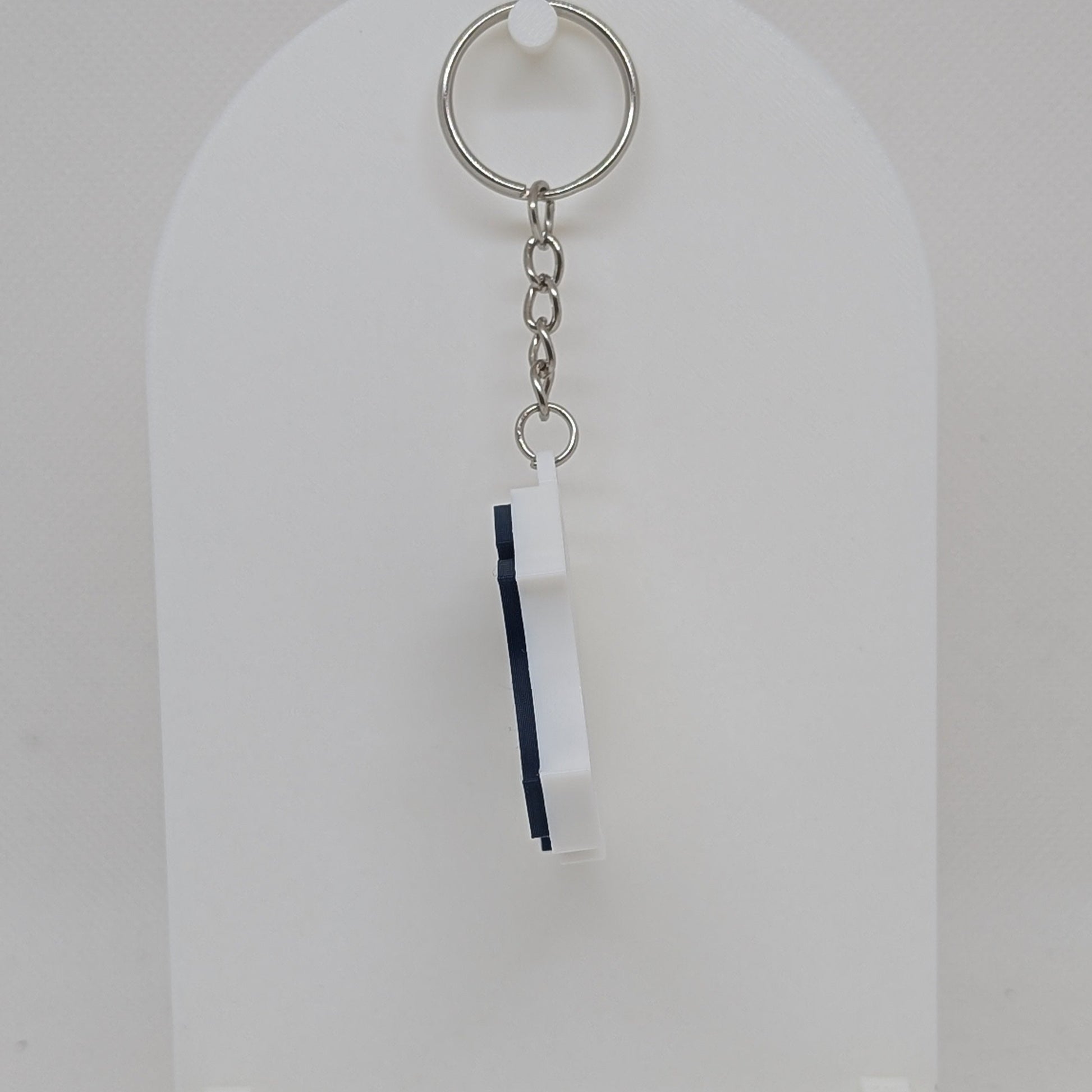 Keychain with a white and blue tag on a white stand against a white background