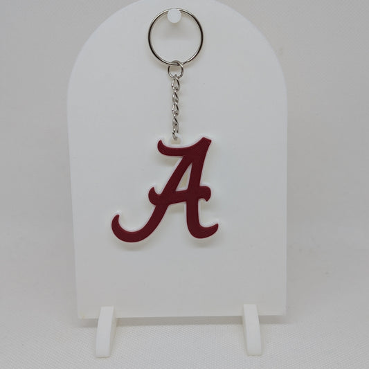 Keychain with a red 'A' on a white stand against a light gray background
