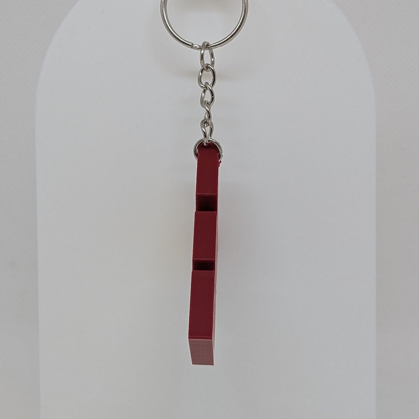 Keychain with a red and black striped design on a white stand