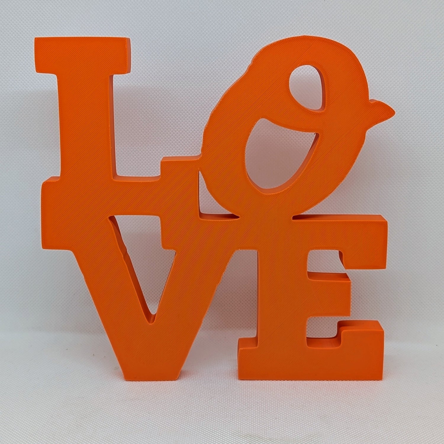 Orange 'LOVE' letter sculpture on a white background