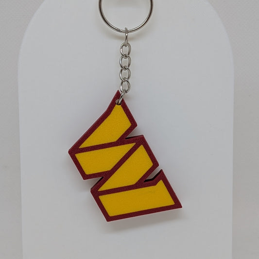 Keychain with yellow and red design on a white stand